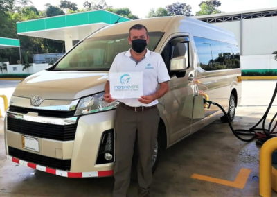 Conductor vestido con el uniforme de Morpho Vans, de pie frente a una camioneta Toyota, Cartel de sujeción utilizado para recoger pasajeros